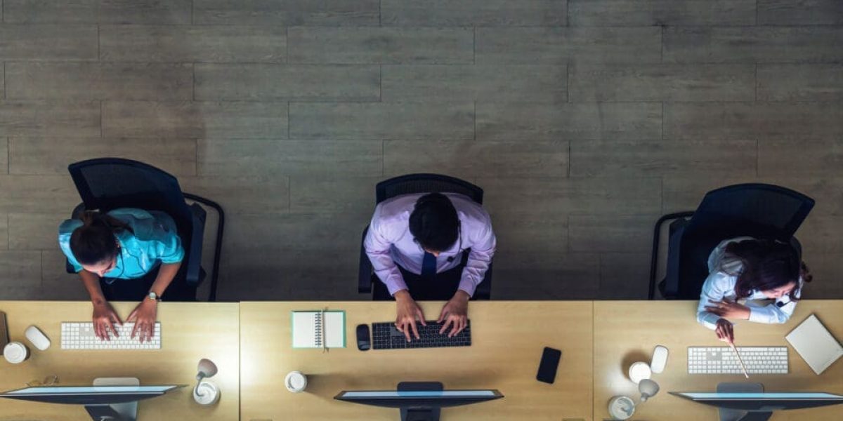 Top view of Asian Male customer care service working hard late in night shift at office,call center department,worker and overtime,team work with colleagues for success concept